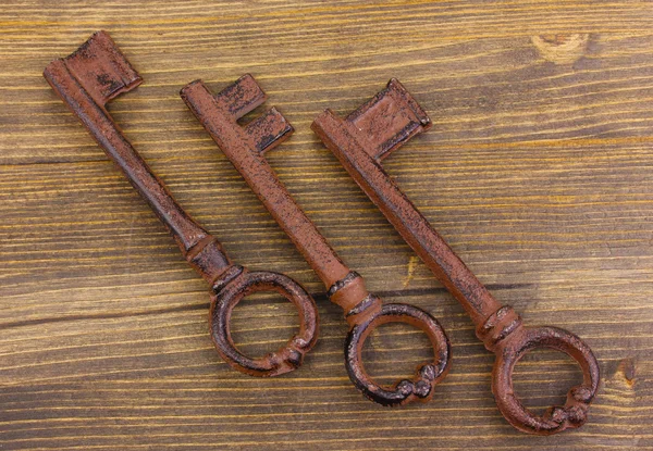 Три старинных ключа на деревянном фоне — стоковое фото