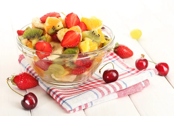 Skål med färsk frukt sallad och bär på vita träbord — Stockfoto