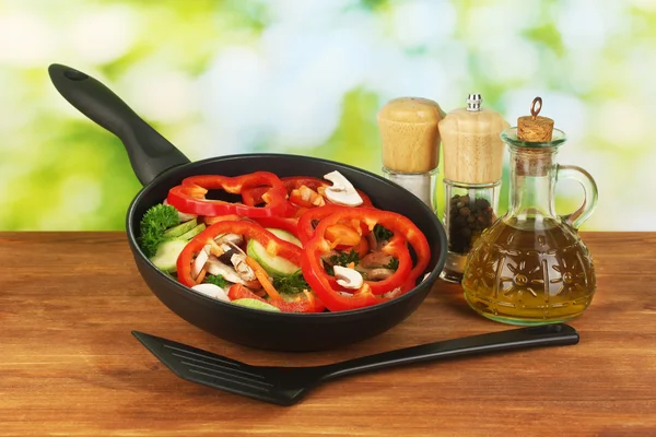 Сковородка с овощами на зеленом фоне — стоковое фото