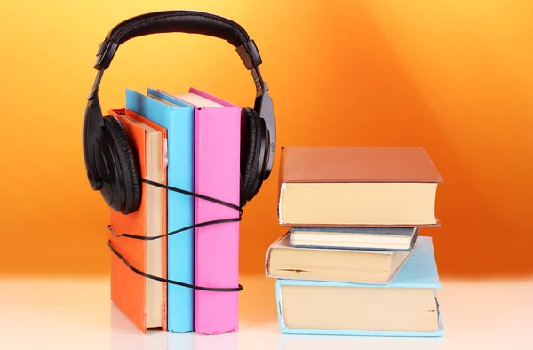 Kopfhörer auf Büchern auf orangefarbenem Hintergrund — Stockfoto