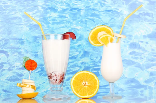 Lækker mælk ryste med frugt på bordet på blå hav baggrund - Stock-foto
