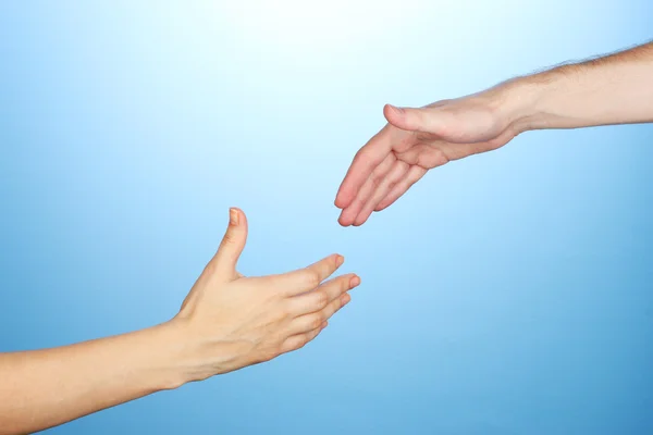 Women's hand går till mannens hand på blå bakgrund — Stockfoto