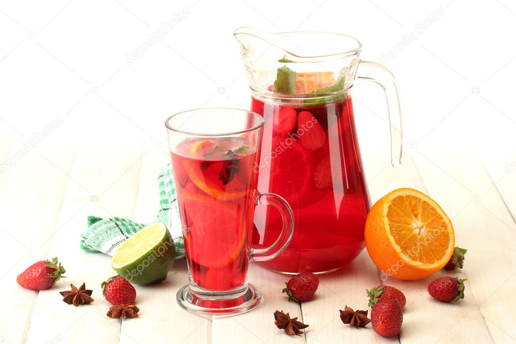 Sangria in jar and glass with fruits, on white wooden table, isolated on white