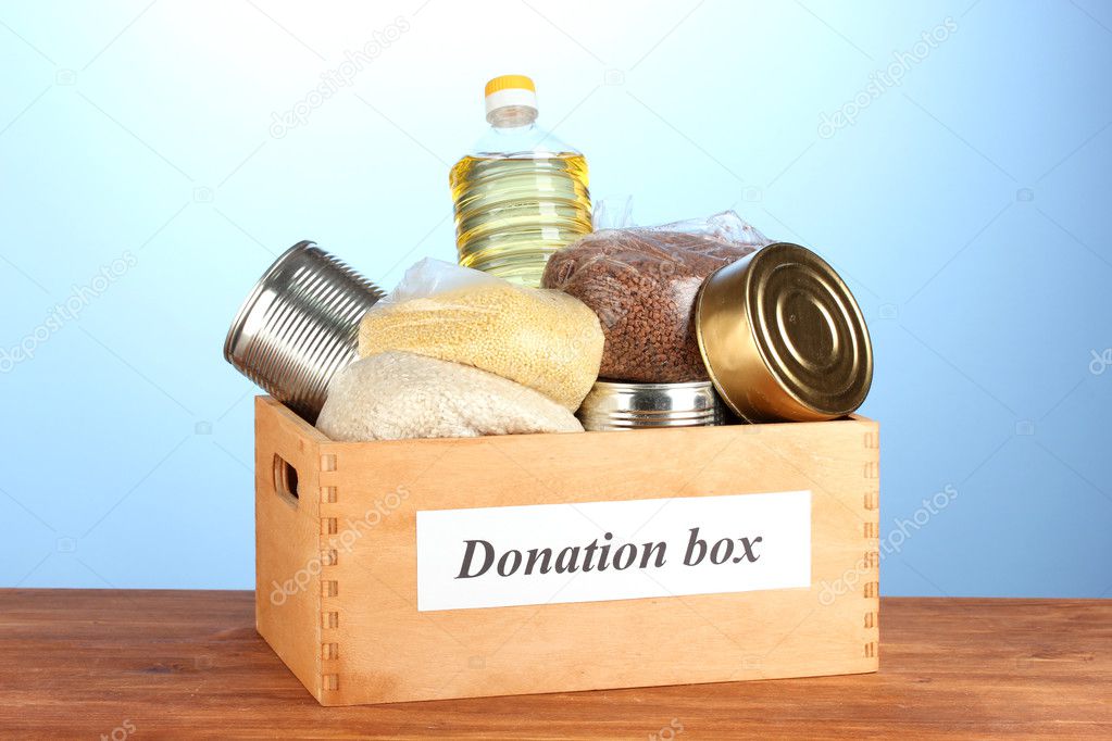 Donation box with food on blue background close-up