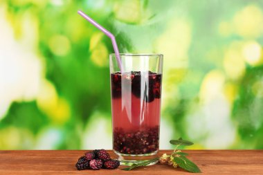 Glass of refreshing mulberry juice on wooden table on green background close-up clipart