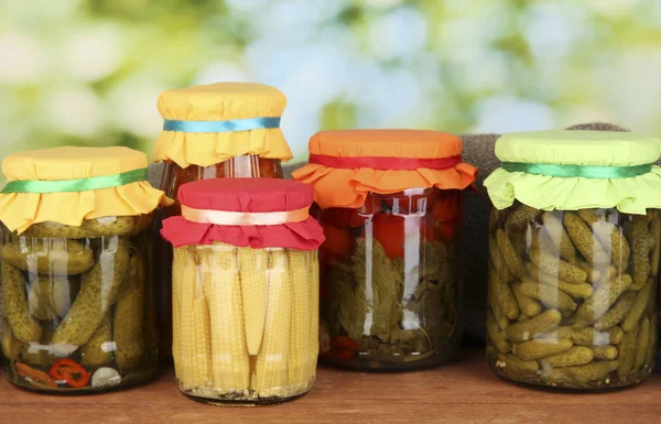 Frascos com legumes enlatados no fundo verde close-up — Fotografia de Stock