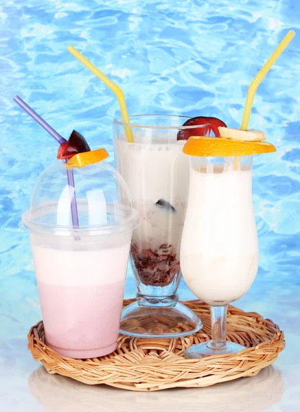Deliciosos batidos de leche con fruta en cuna de mimbre sobre fondo azul marino — Foto de Stock
