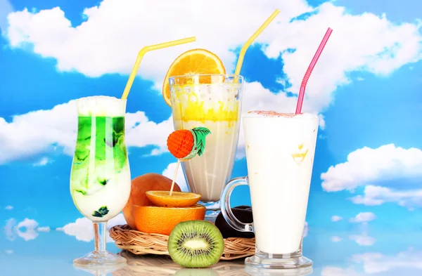 Вкусные молочные коктейли с фруктами на плетеной колыбели на фоне неба — стоковое фото