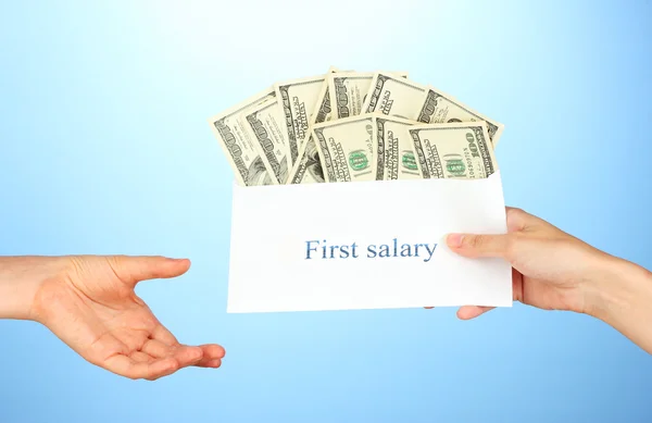 stock image Woman's hand passes the envelope with the salary on blue background