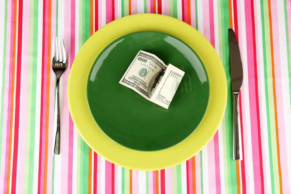 Банкноты на тарелке на полосатой скатерти крупным планом — стоковое фото