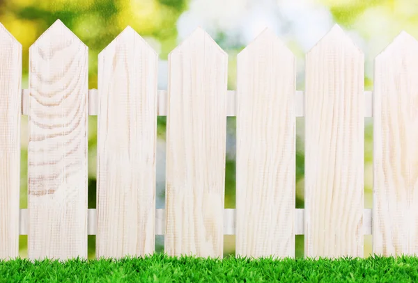 Wooden fence and green grass on bright background — Stock Photo, Image