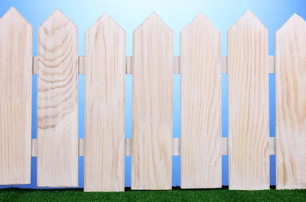 木製のフェンスと青色の背景に緑の草 — ストック写真