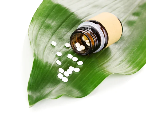 Tabletten auf grünem Blatt mit Flasche isoliert auf weißem Blatt — Stockfoto