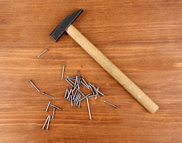 Martelo e unhas de metal no fundo de madeira — Fotografia de Stock