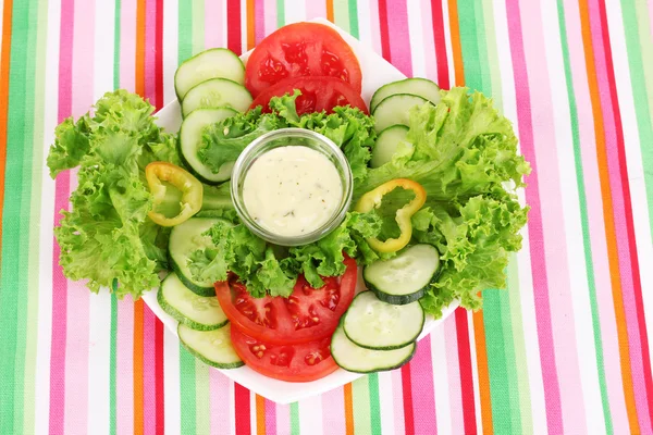 Doğranmış sebzeler ve sos plaka üzerinde çizgili masa örtüsü — Stok fotoğraf