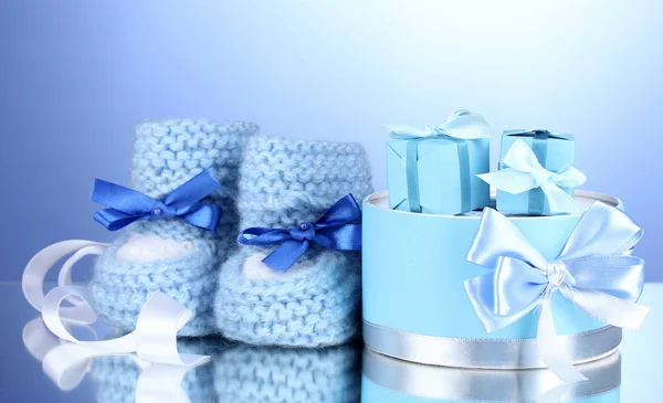 Schöne Geschenke und Babystiefel auf blauem Hintergrund — Stockfoto