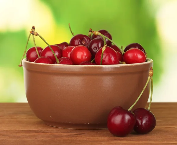 棕绿色背景上的木桌上的碗里的樱桃 — 图库照片