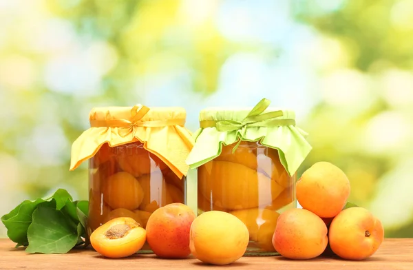 在罐子罐头的杏子、 甜杏绿色背景上的木桌上 — 图库照片