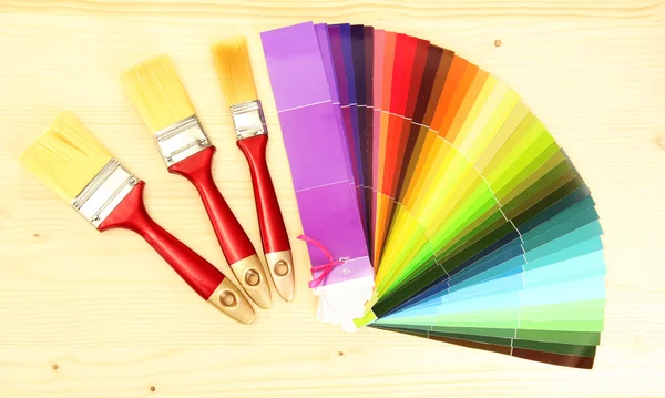 Paint brushes and bright palette of colors on wooden background — Stock Photo, Image