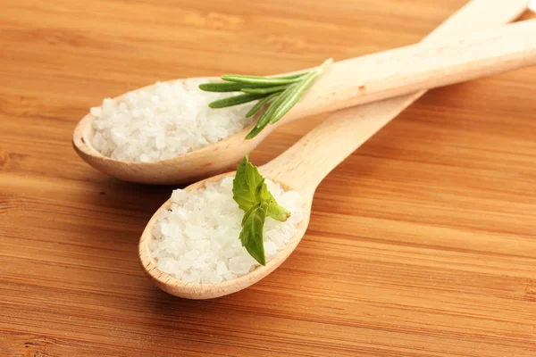 Salz in Löffeln mit frischem Rosmarin und Basilikum auf Holzgrund — Stockfoto