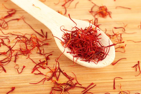 Stigmas of saffron in wooden spoon on wooden background close-up — Stock Photo, Image