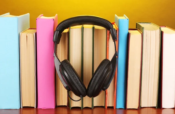 Навушники на книгах на дерев'яному столі на жовтому фоні — стокове фото
