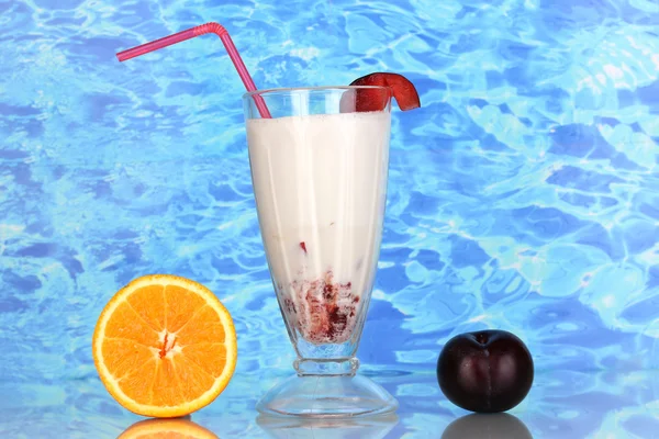 Heerlijke milkshake met fruit op tafel op blauwe zee achtergrond — Stockfoto