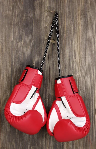Røde boksehansker hengende på trebakgrunn – stockfoto