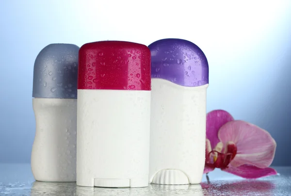 Deodorants with flower on blue background — Stock Photo, Image