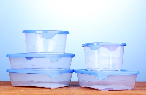 Envases de plástico para alimentos sobre mesa de madera sobre fondo azul —  Fotos de Stock