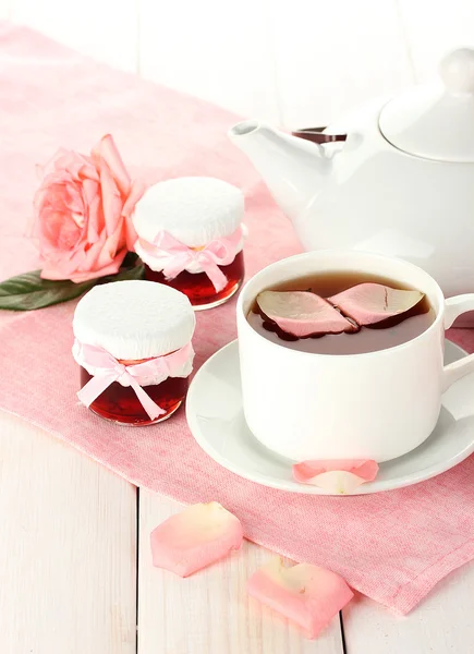 Tetera y taza de té con rosas y mermelada sobre mesa de madera blanca —  Fotos de Stock