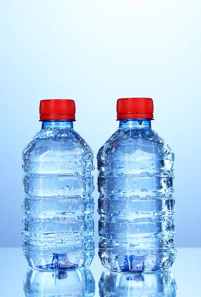 Plastové lahve s vodou na modrém pozadí — Stock fotografie