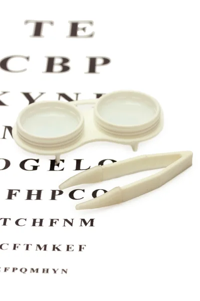 Kontaktlinsen in Behältern und Pinzetten, auf Schlangenaugendiagramm-Hintergrund — Stockfoto