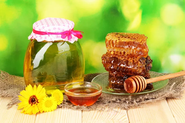 Tarro de miel y panal sobre mesa de madera sobre fondo natural —  Fotos de Stock