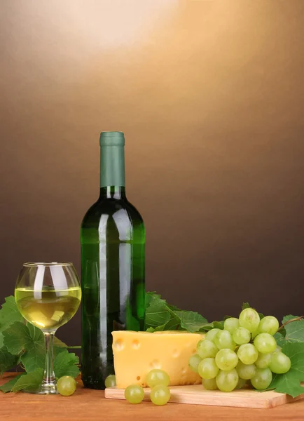 Flaska bra vin med glas och ost på träbord på brun bakgrund — Stockfoto