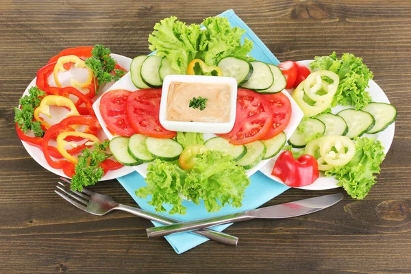 Gehacktes Gemüse und Soße auf Teller auf Holztisch — Stockfoto