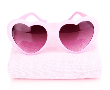 Pink heart-shaped sunglasses on towel isolated on white clipart