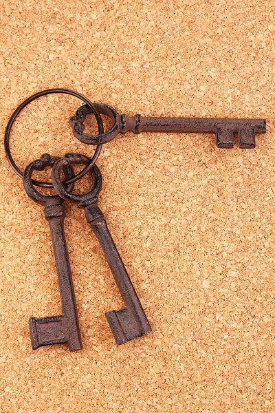 Um monte de chaves antigas no fundo de cortiça — Fotografia de Stock