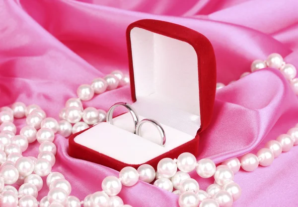在红色框粉色布背景上的结婚戒指 — 图库照片