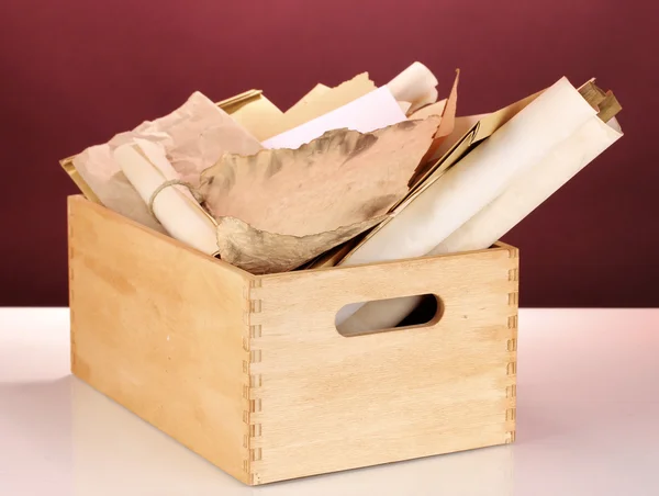 Wooden crate with papers and letters on red background — Stock Photo, Image