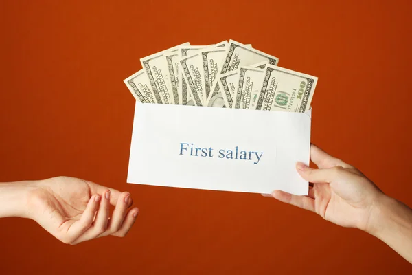 stock image Woman's hand passes the envelope with the salary on brown background