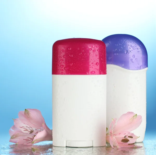 Deodoranty s květinami na modrém pozadí — Stock fotografie