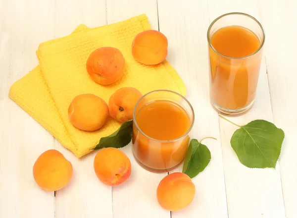 Verres de jus d'abricot et d'abricots frais sur table en bois blanc — Photo