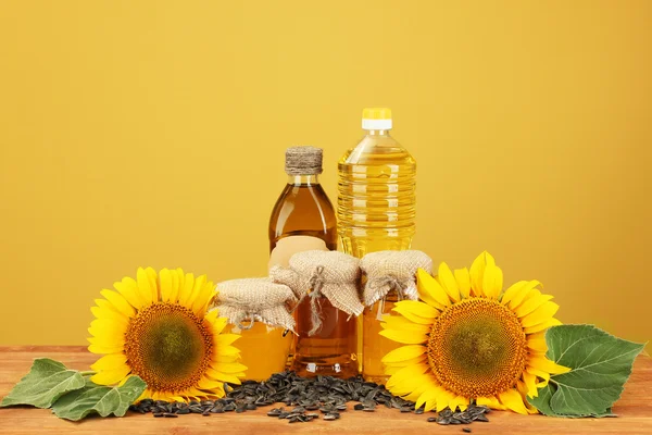 Olej slunečnicový a sunflower na žlutém podkladu — Stock fotografie