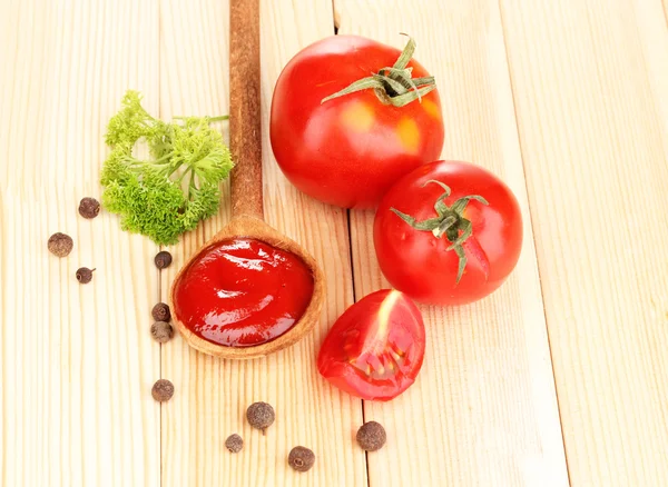 Ketchup en rijpe tomaten op houten tafel — Stockfoto