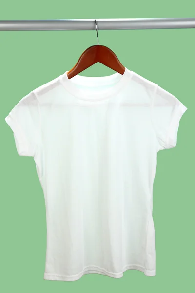 Weißes T-Shirt auf Kleiderbügel auf grünem Hintergrund — Stockfoto