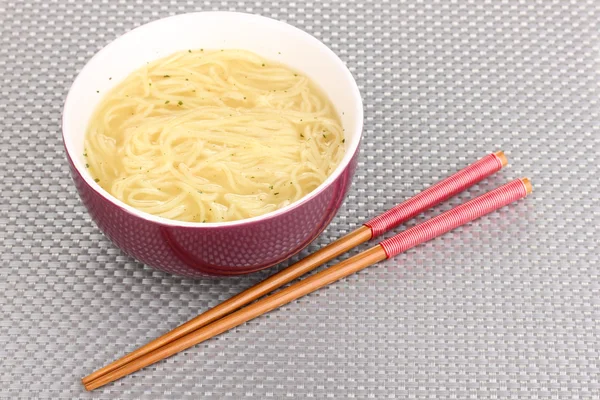 Asian noodles in bowl on grey mat — Stock Photo, Image