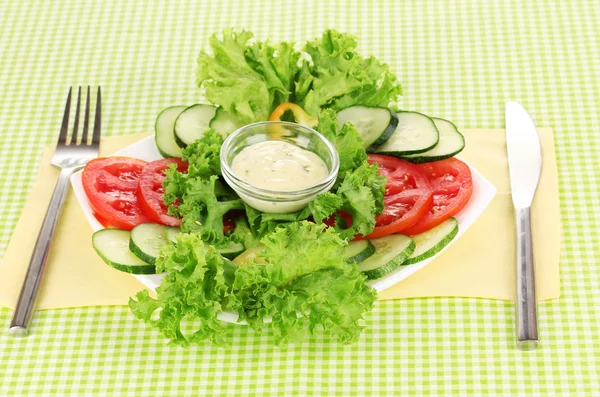 Нарезанные овощи и соус на тарелке на зеленой скатерти — стоковое фото