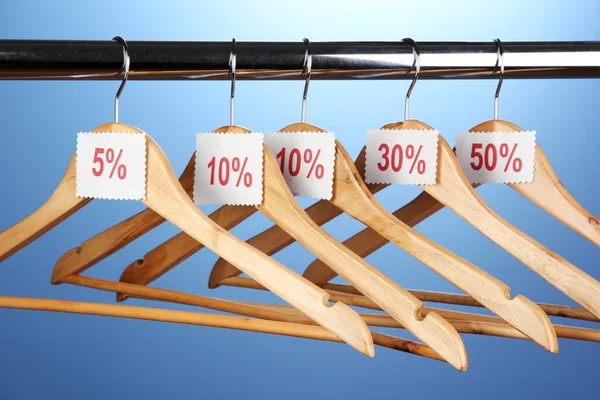 Wooden clothes hangers as sale symbol on blue background — Stock Photo, Image