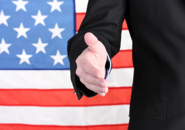 Homme d'affaires donnant sa main pour une poignée de main sur fond drapeau américain — Photo